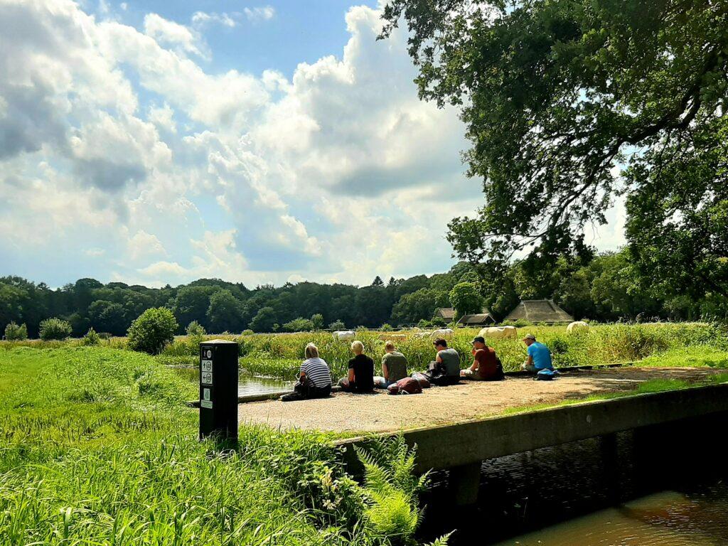 Wandelaars rusten uit op een bruggetje in de natuur